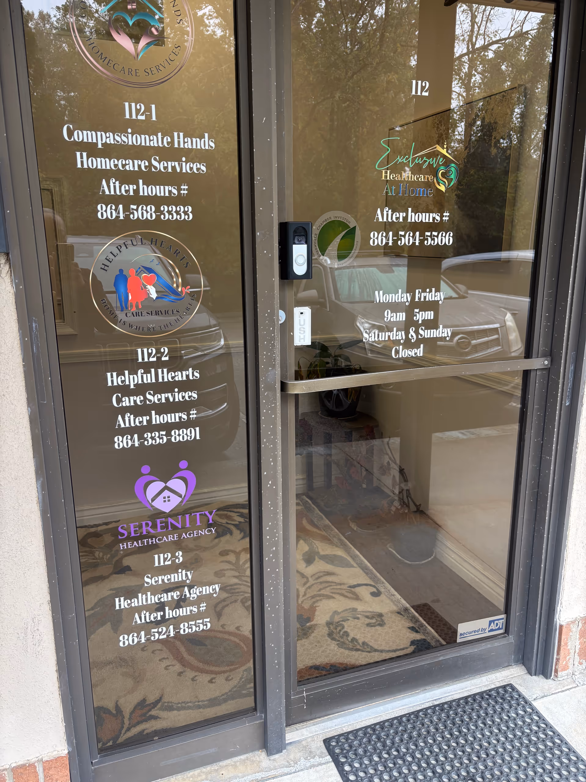Glass entrance doors display Serenity Healthcare Agency signage and after-hours contact numbers.