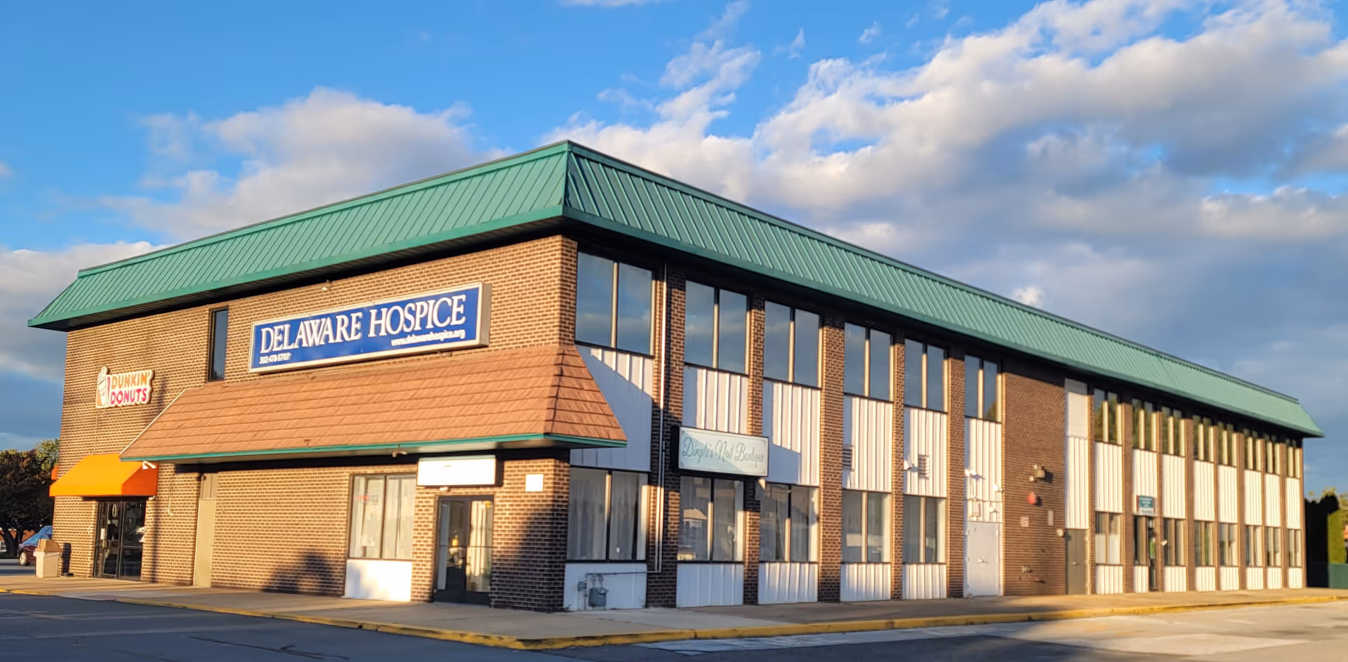 A brick hospice building with a green roof and Delaware Hospice sign.