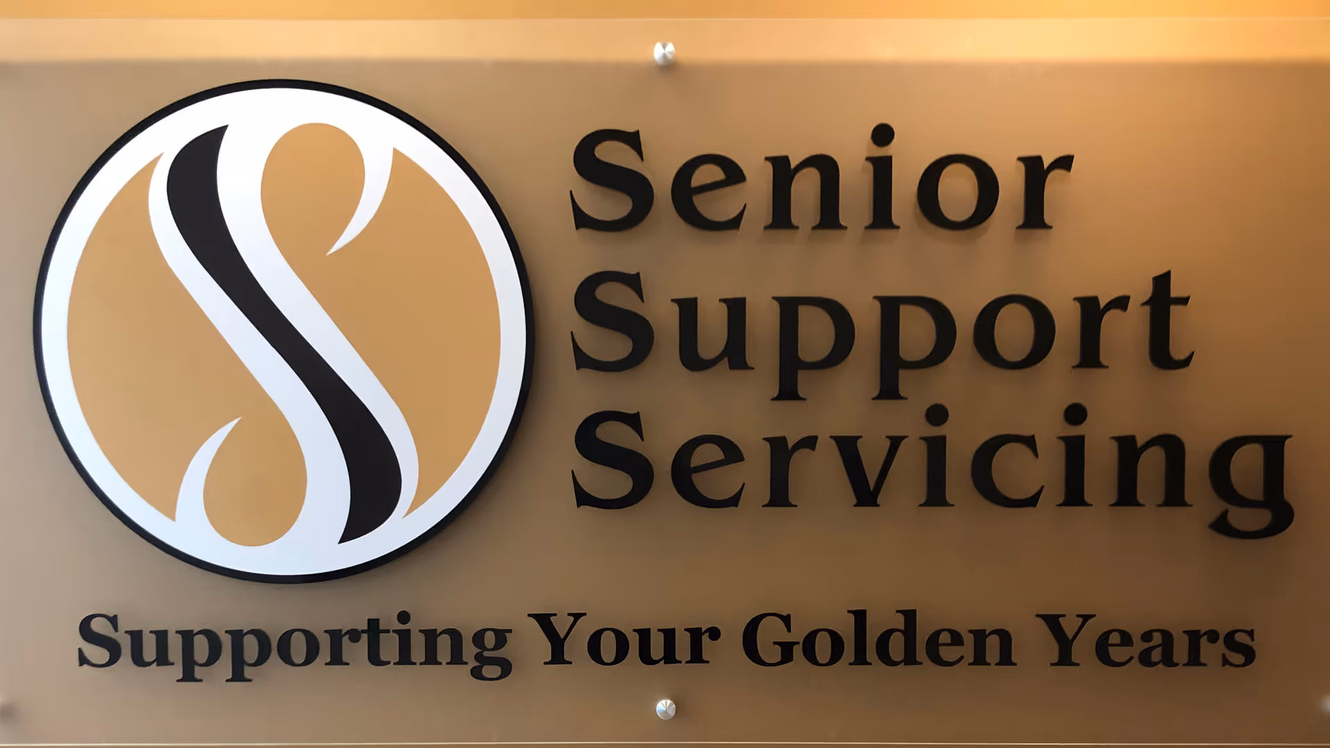 Gold-toned wall sign with circular logo and Senior Support Servicing lettering.