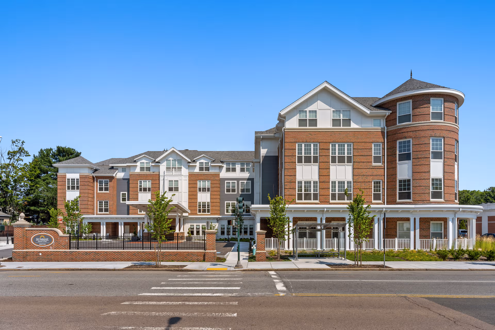 Front exterior of Sunrise of Newton senior living facility along a busy street.