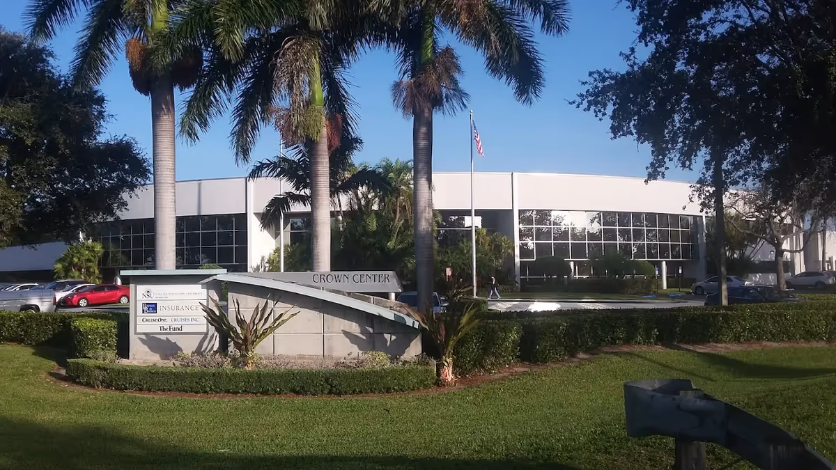 Modern single-story building with glass windows, palm trees, and a sign reading Crown Center in front.