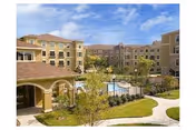 Exterior view of Evergreen at Plano with courtyard, pool, palm trees, and surrounding buildings.