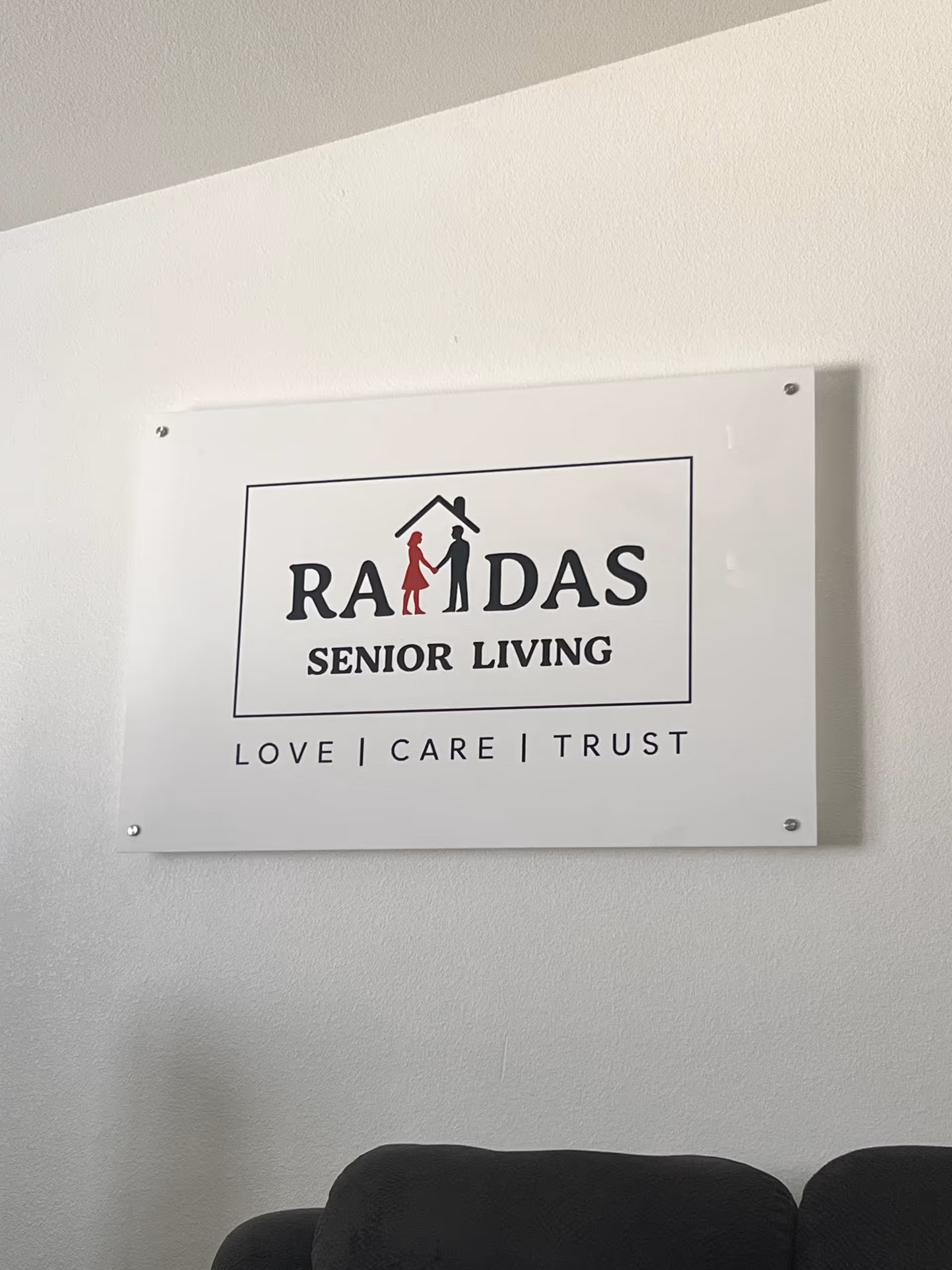 White RAMDAS SENIOR LIVING sign mounted on a light wall indoors.