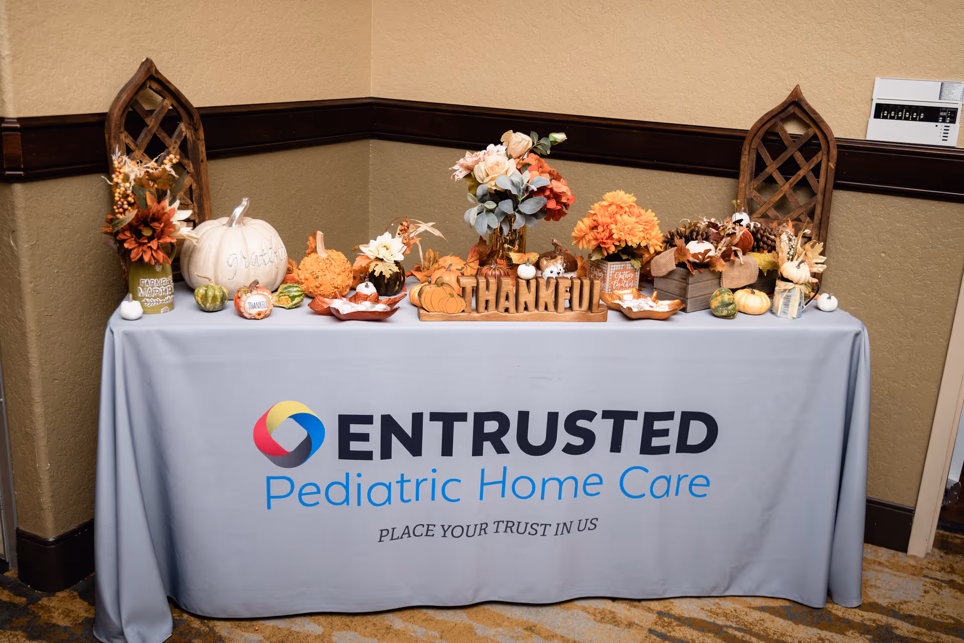 Display table with Entrusted Pediatric Home Care branding and autumn decor.