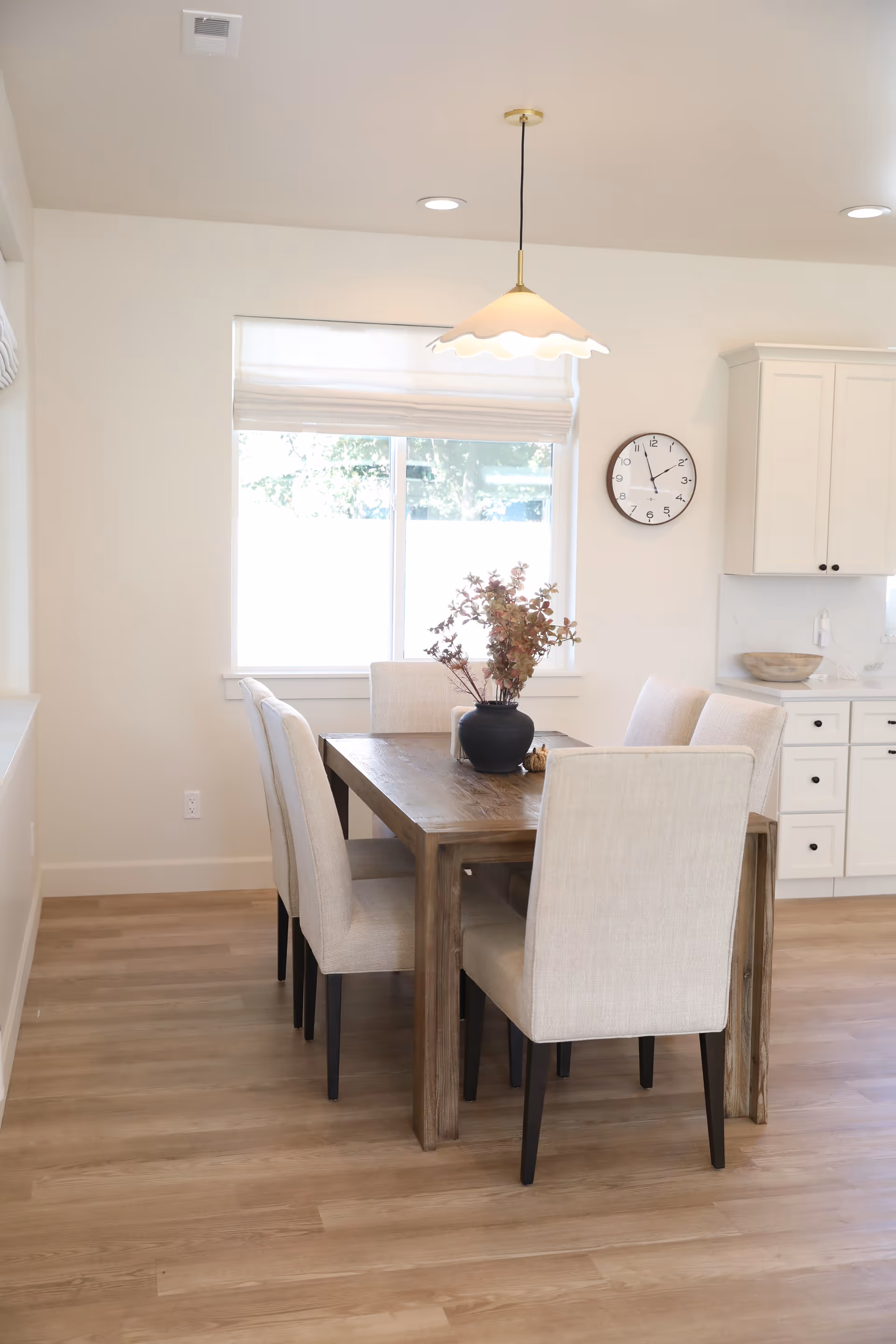 Sunlit dining room with a wooden table and beige upholstered chairs.