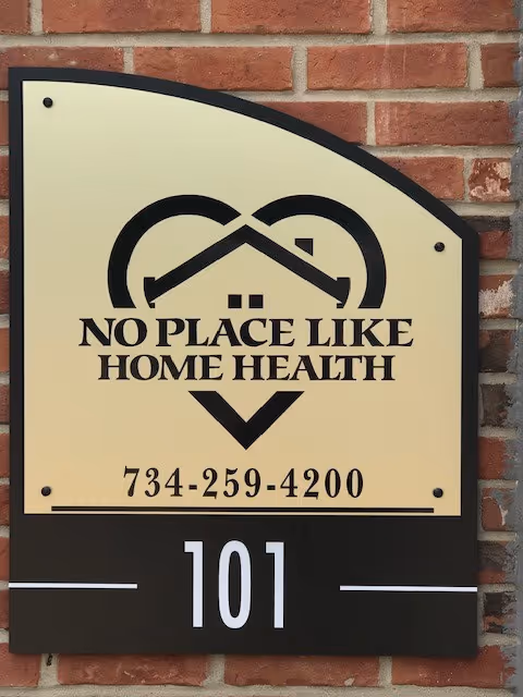 Sign on brick exterior reads No Place Like Home Health with phone 734-259-4200 and 101.