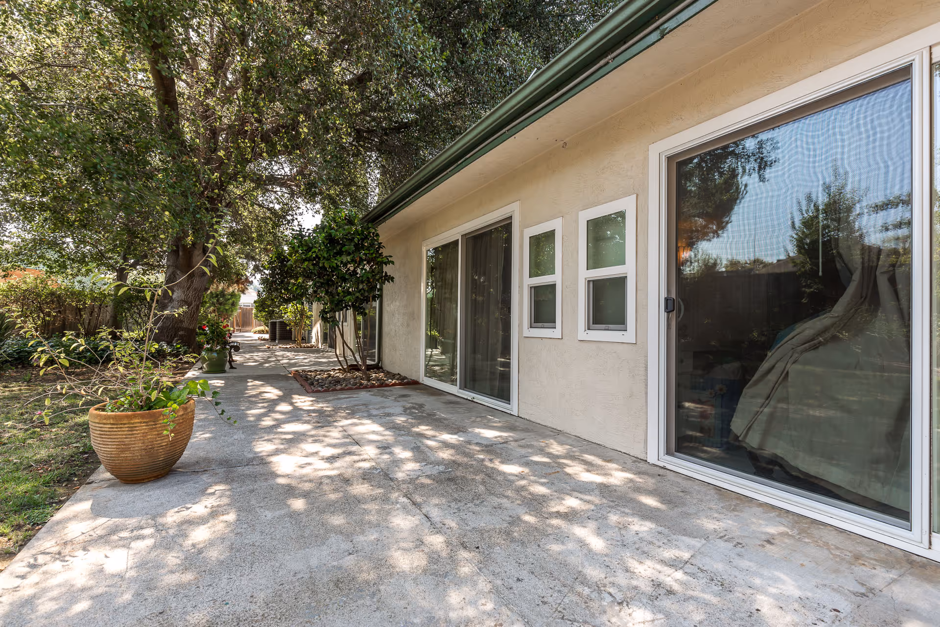 Exterior of a care center with a concrete patio, sliding doors, and trees.