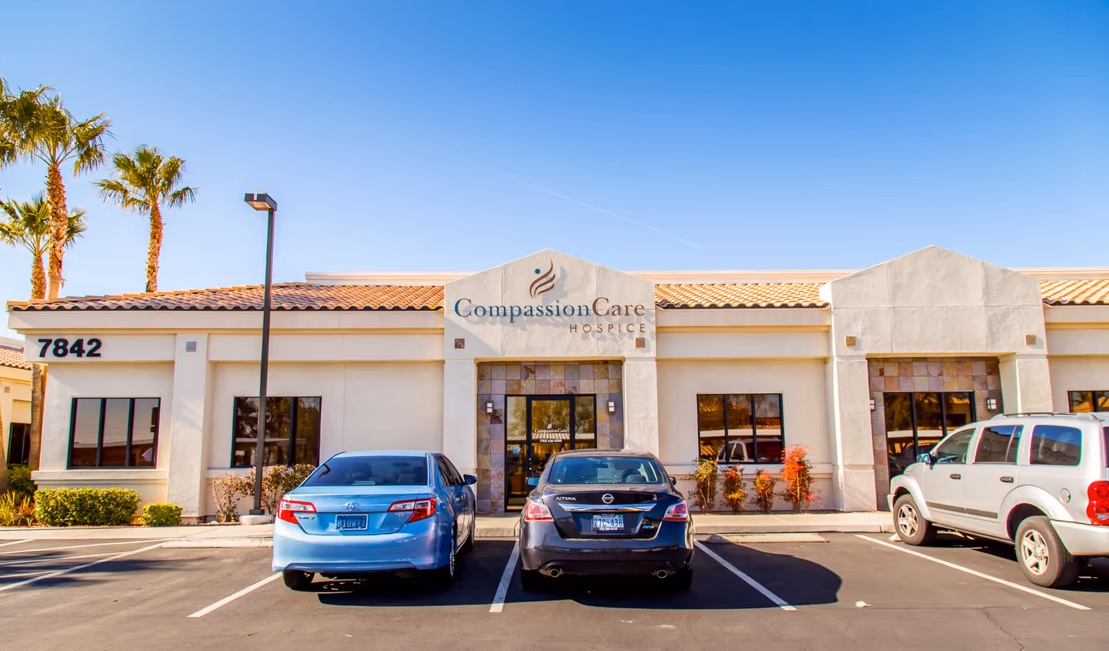 Exterior view of CompassionCare Hospice building with parked cars in front.