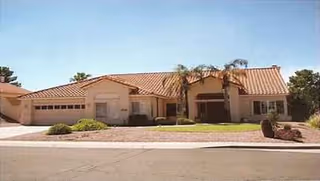 Single-story beige senior living facility with a red-tiled roof and palm trees.