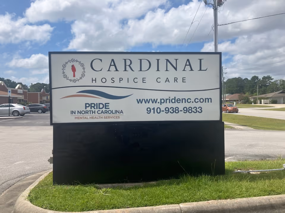 Large outdoor sign reading Cardinal Hospice Care with Pride in North Carolina logo.