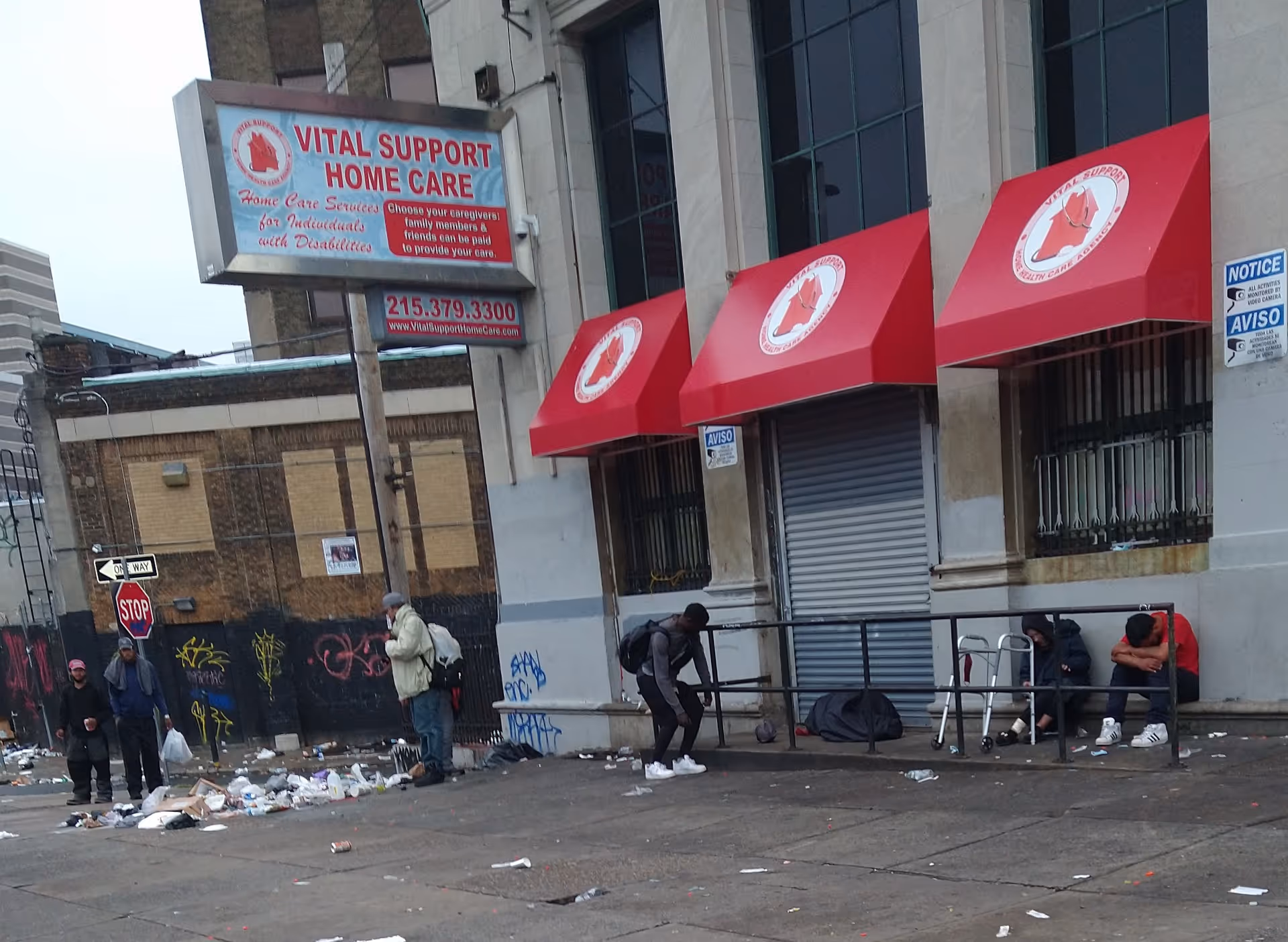 Urban building storefront with Vital Support Home Care sign, red awnings, and people nearby.
