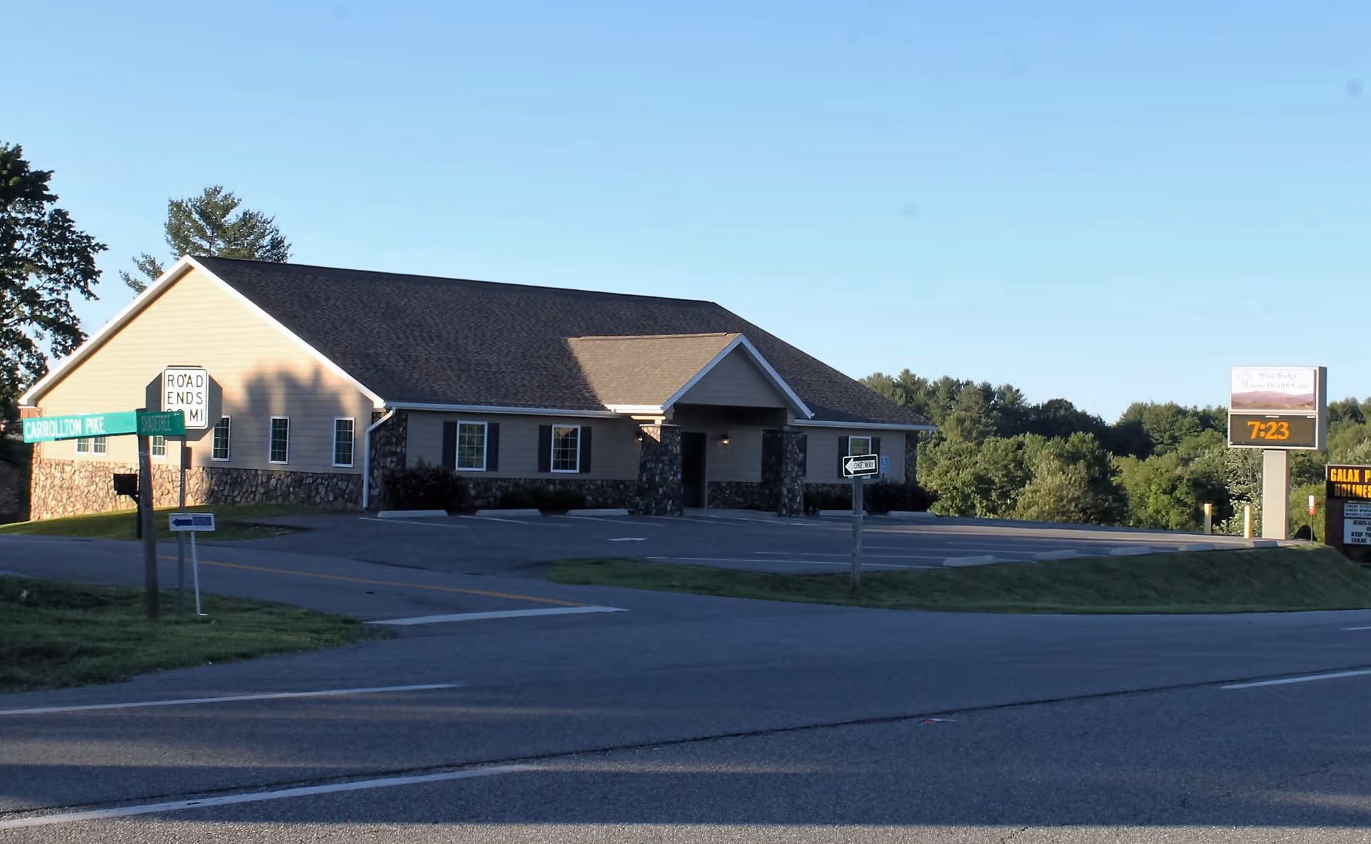 Single-story healthcare building with stone accents and a parking lot at a street corner.