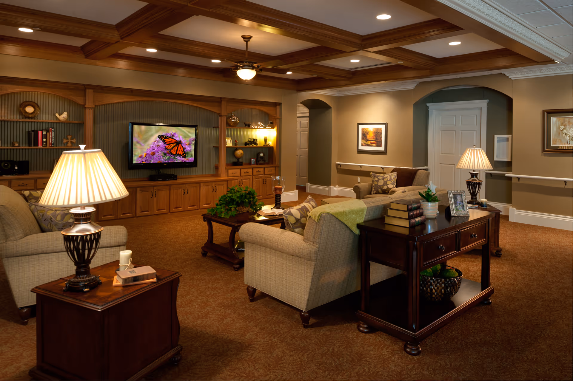 Cozy senior living lounge with sofas, lamps, and a wooden entertainment cabinet.