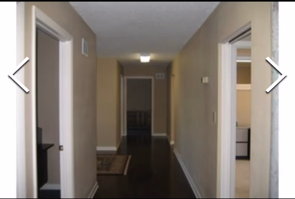 Long indoor hallway in a senior living facility with doors along both walls.