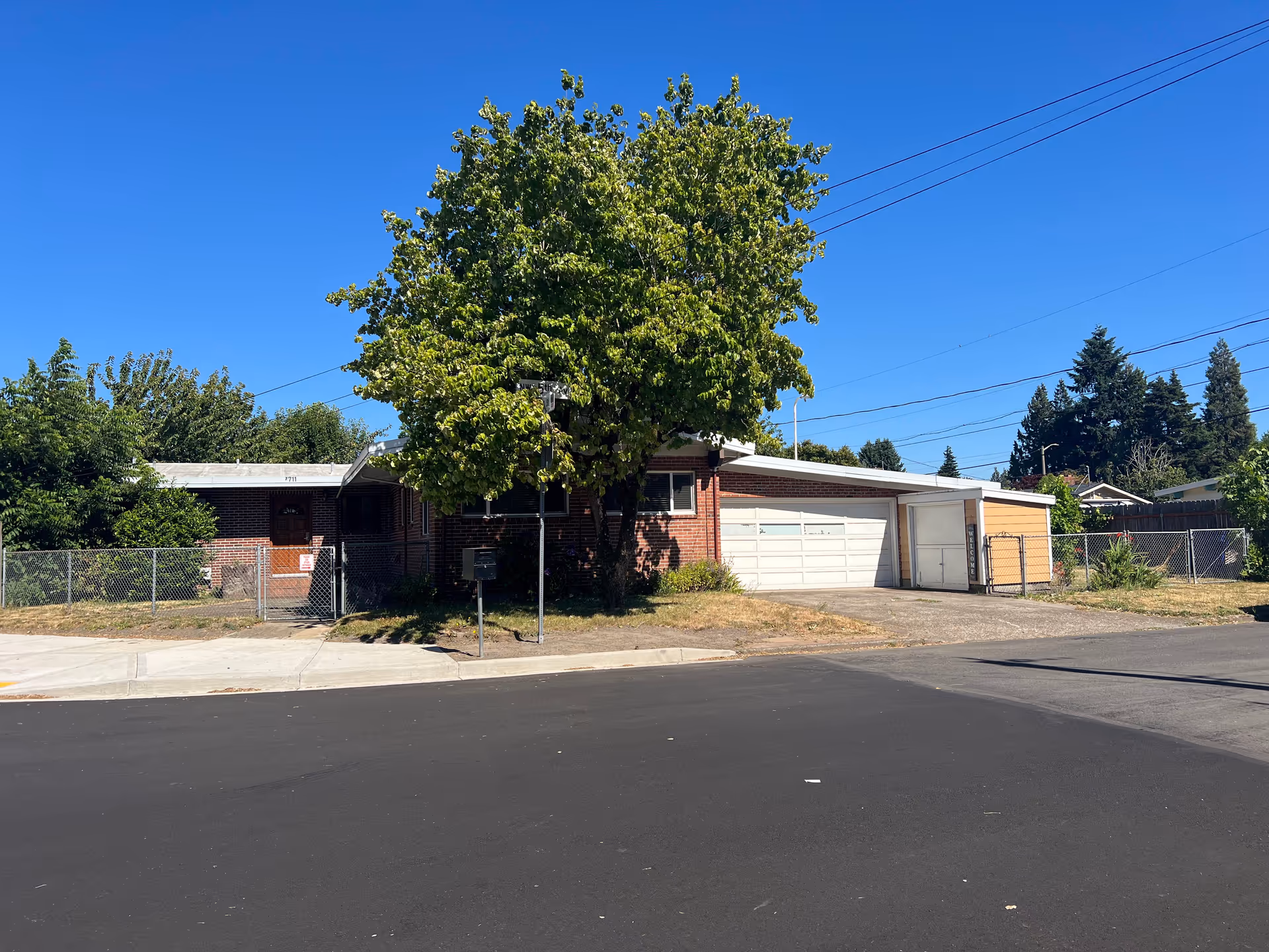 Front view of Legacy Manor Adult Family Home LLC, a single-story brick building with a tree.