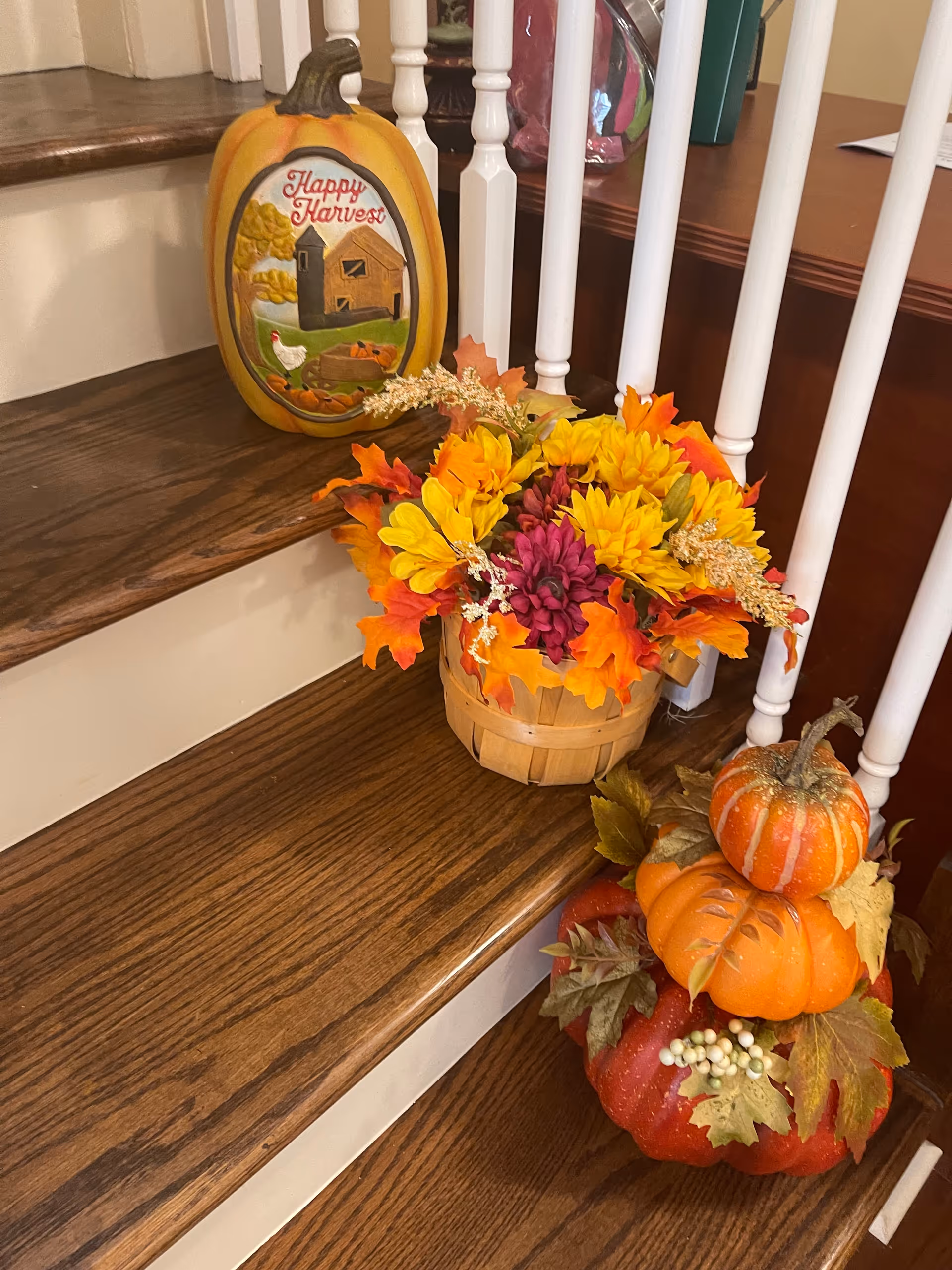 Autumn pumpkins and fall flowers decorate a wooden indoor staircase.
