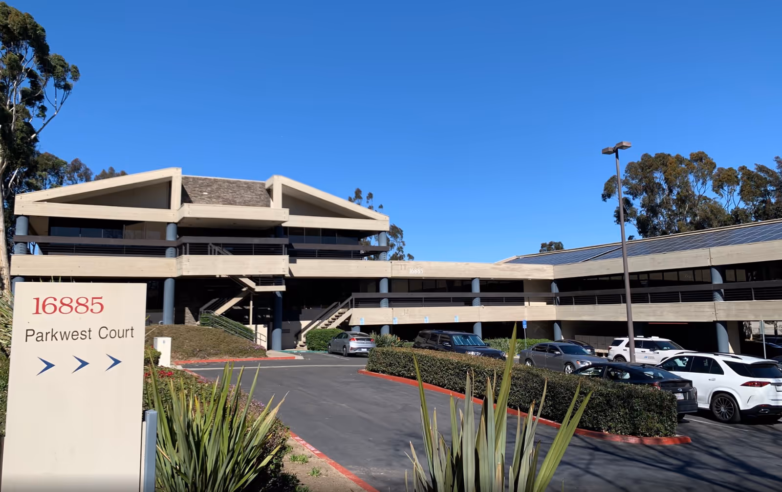 Exterior of a multi-level senior living facility with a parking lot and blue sky.