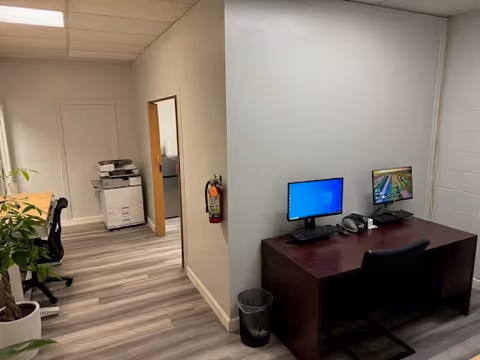 Office area in a senior living facility with two monitors and printer.