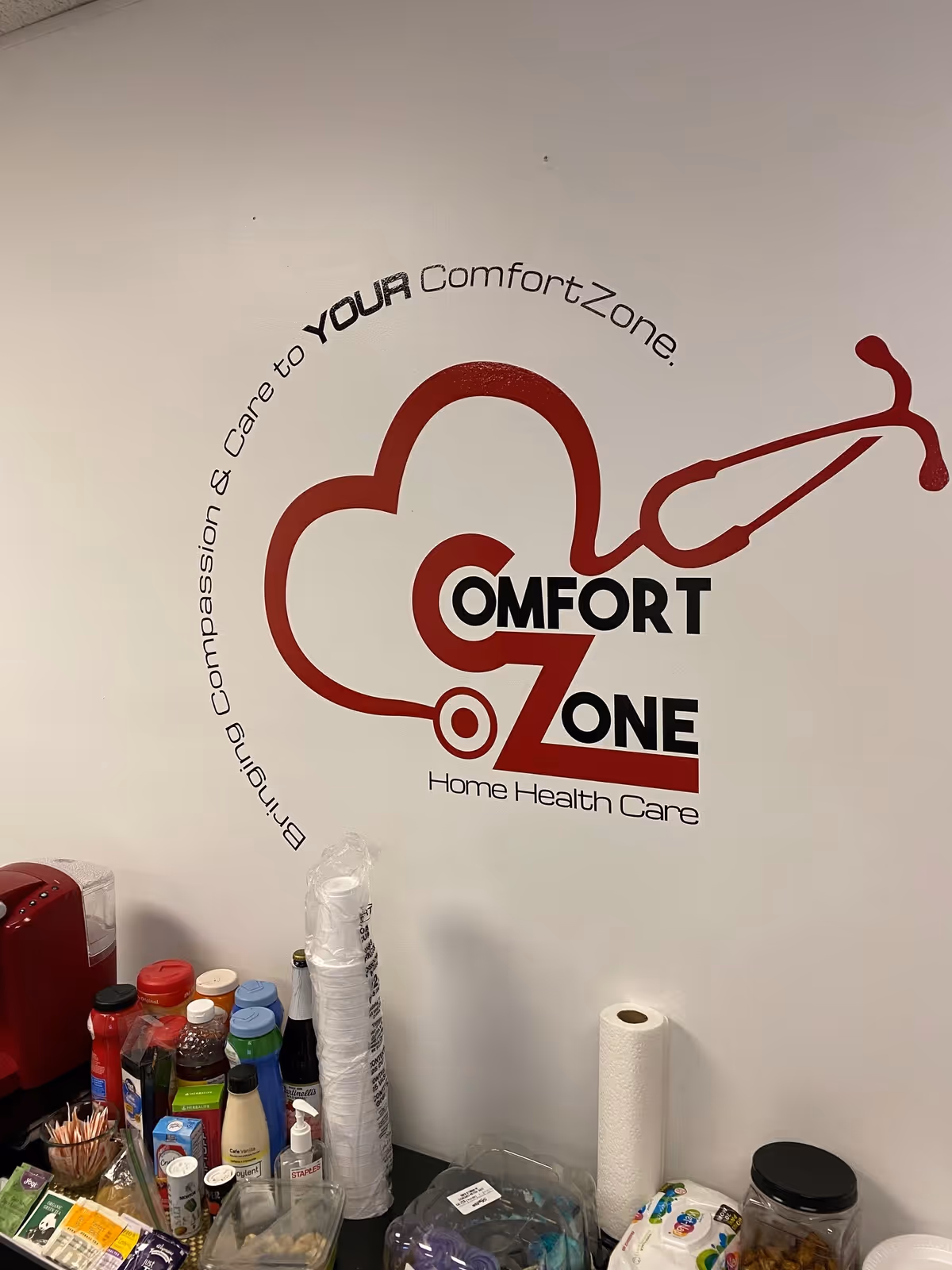 Interior wall with ComfortZone Home Health Care logo and a beverage station.