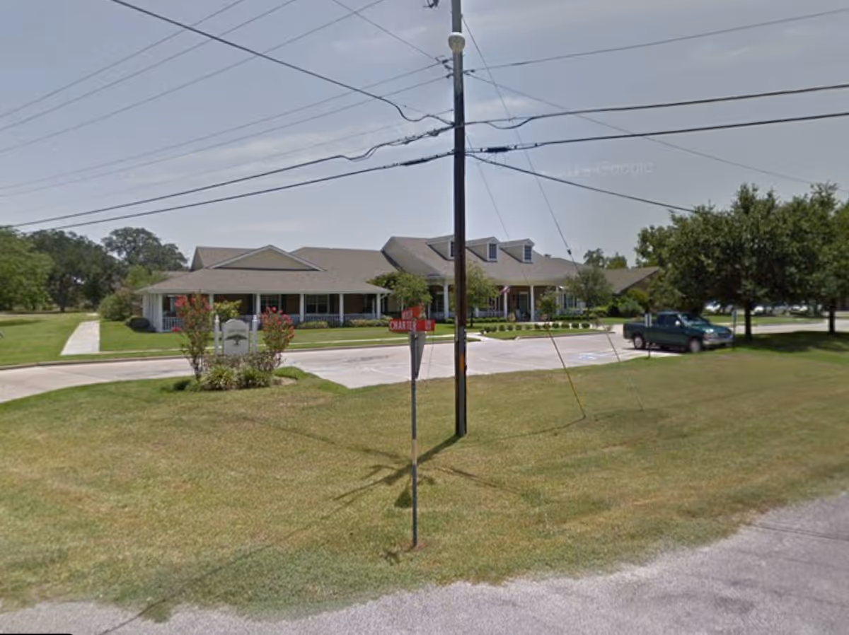 Columbus Oaks Assisted Living exterior: single-story building with entrance, parking, and manicured lawn.