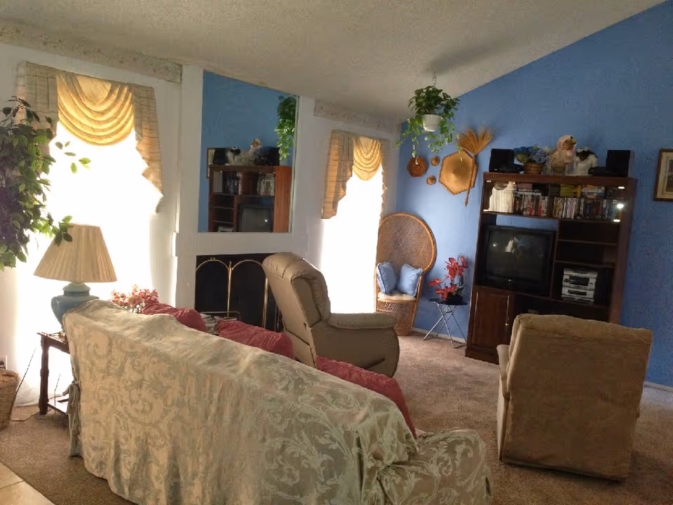 A cozy living room in a senior facility with blue walls, seating, and a TV.