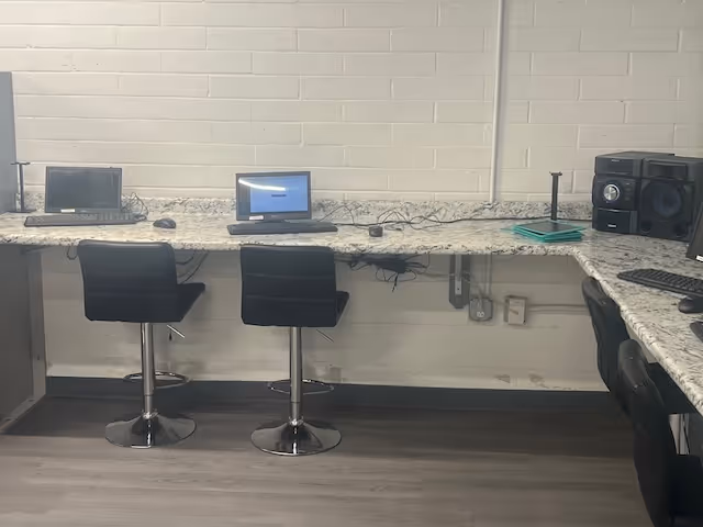 Interior workspace at Medicore Transport & Achievement Centers with laptops on a granite counter and stools.