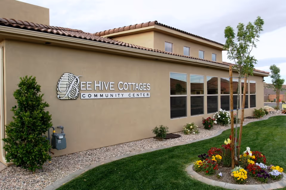 Exterior view of Bee Hive Cottages Community Center with landscaping and sign.
