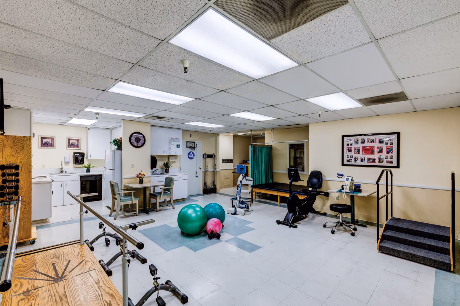 Interior rehab room with exercise equipment, balls, a kitchenette, and seating area.