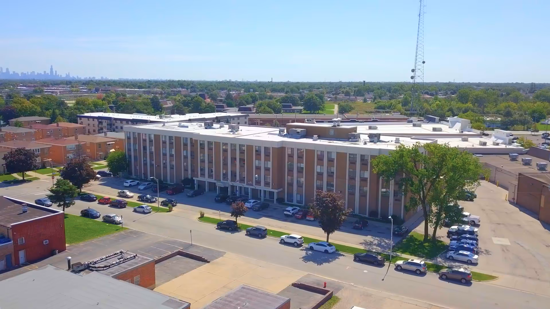 Aerial view of a large, multi-story senior living facility with parking and greenery.