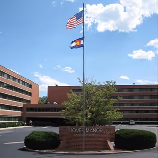 Exterior view of Hover Senior Living Community with flagpole and brick entry sign.