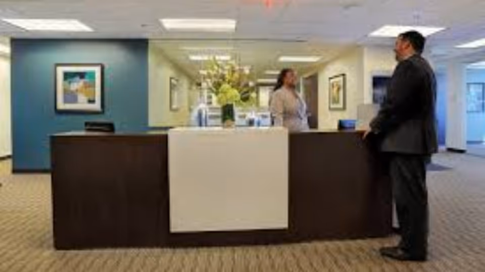 Reception desk in Parker All-Inclusive Care lobby with staff member and visitor.