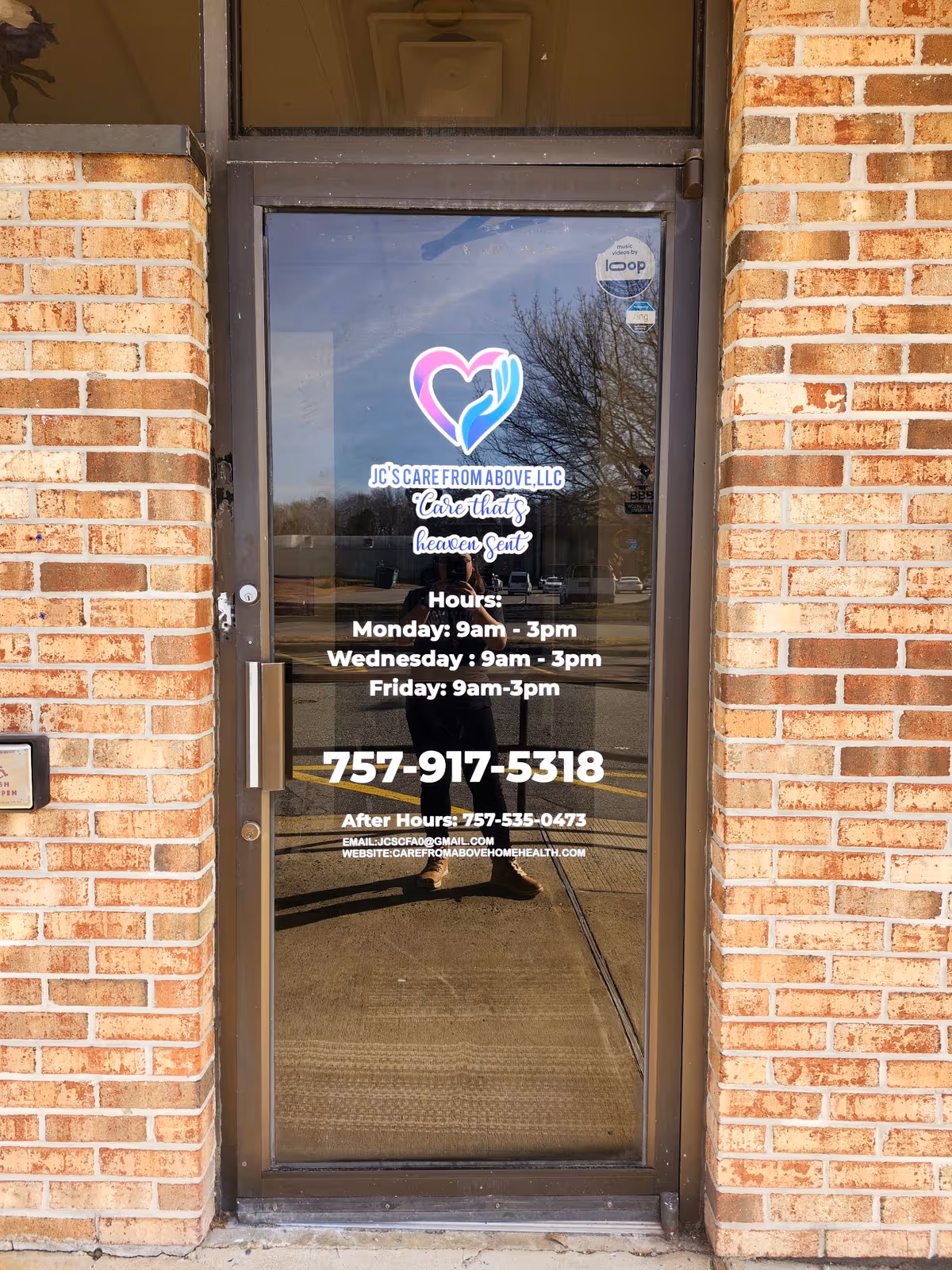 Glass entry door showing facility logo and hours, framed by brick exterior.
