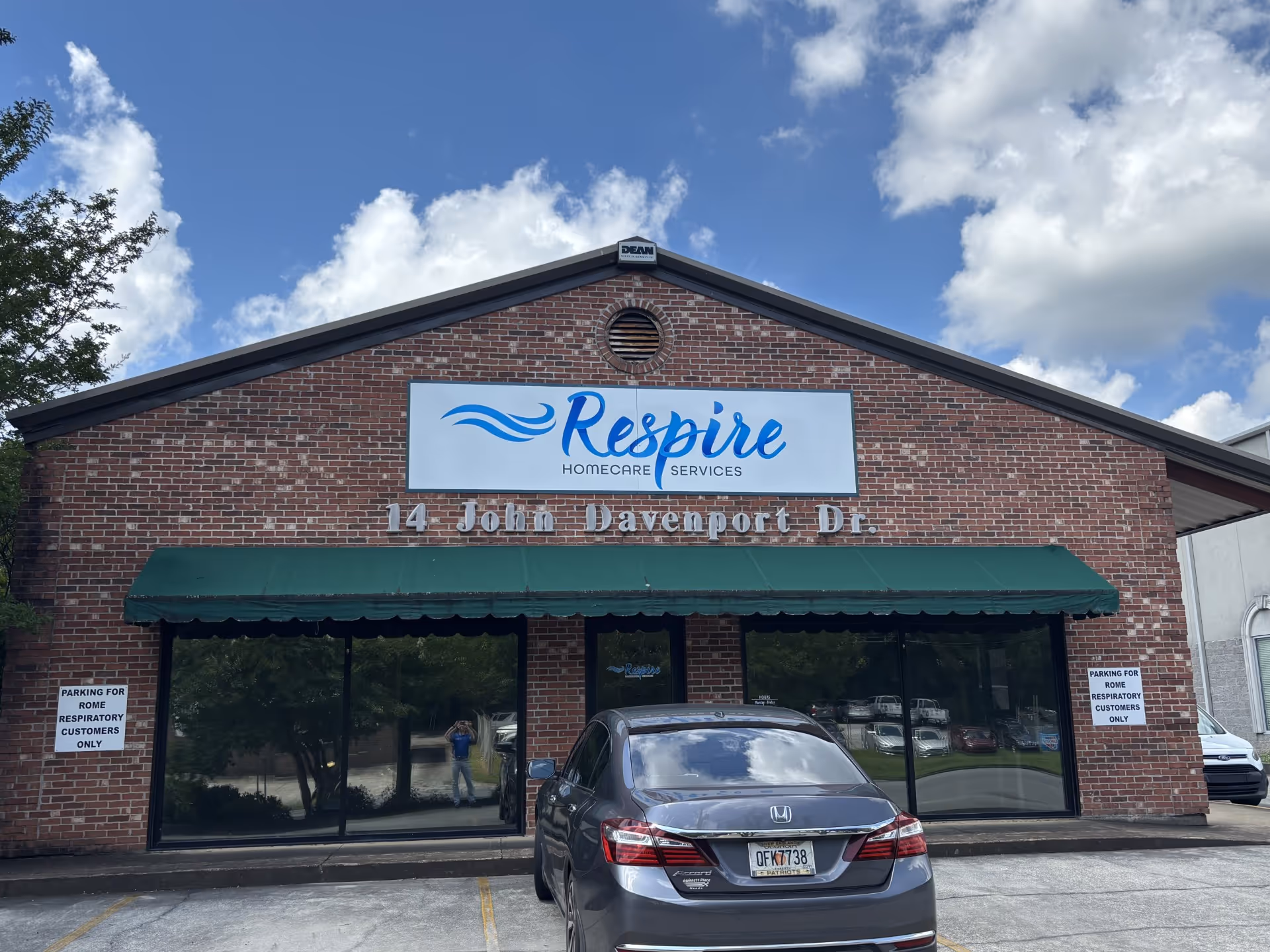 A brick building storefront shows a Respire Homecare Services sign with a parked car.