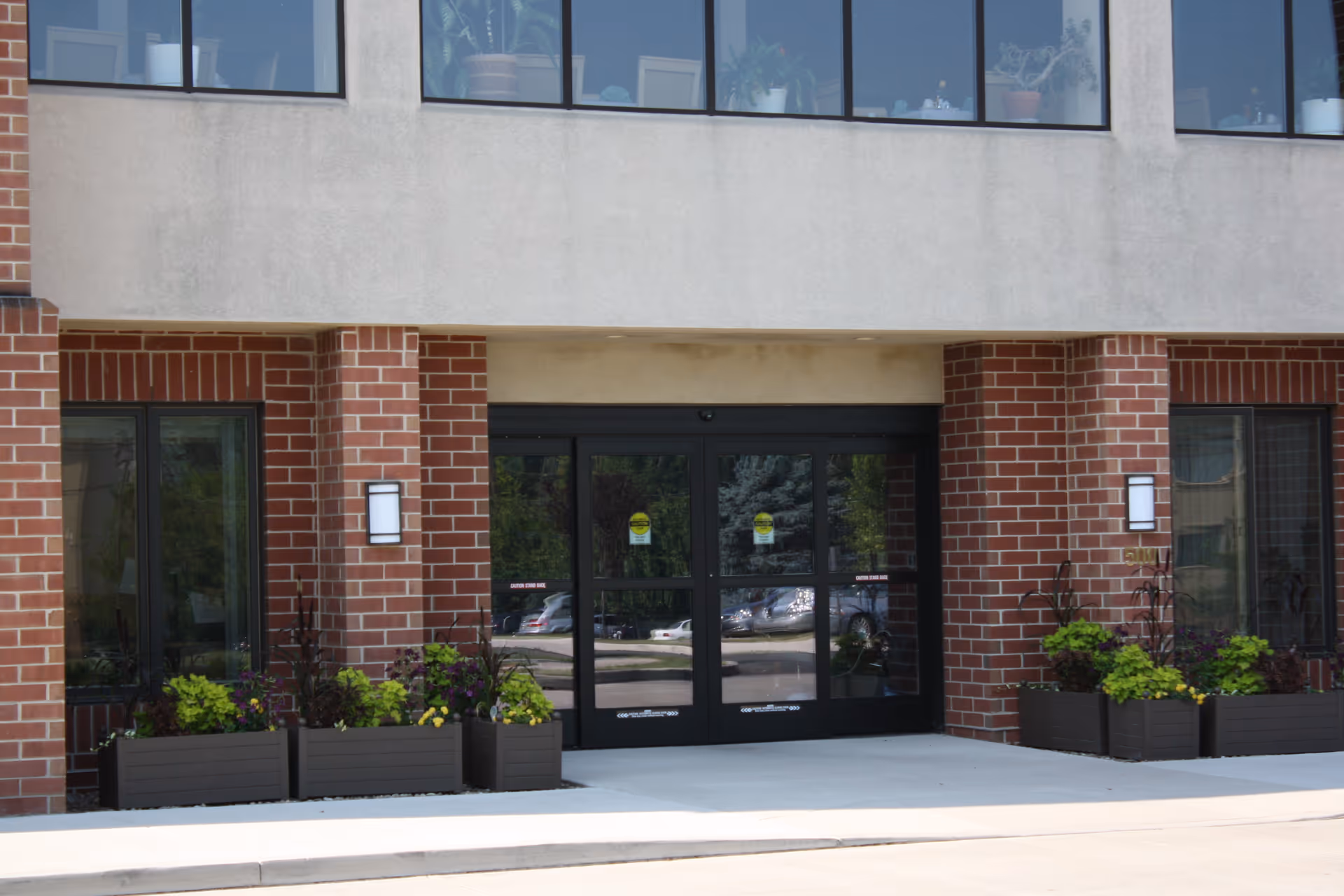 Exterior view of Foxdale Village entrance with glass doors and brick columns.