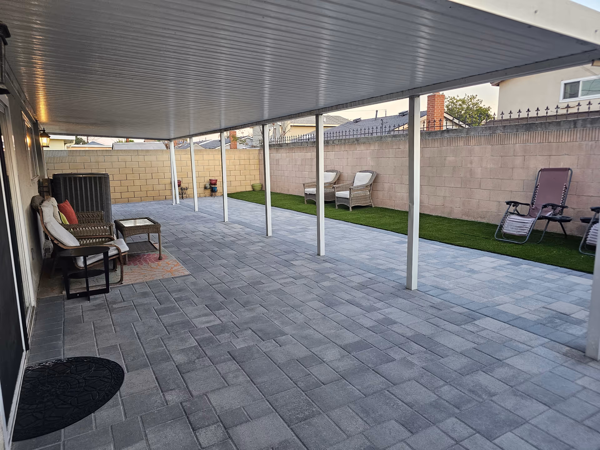 Covered patio with outdoor seating and artificial turf strip.