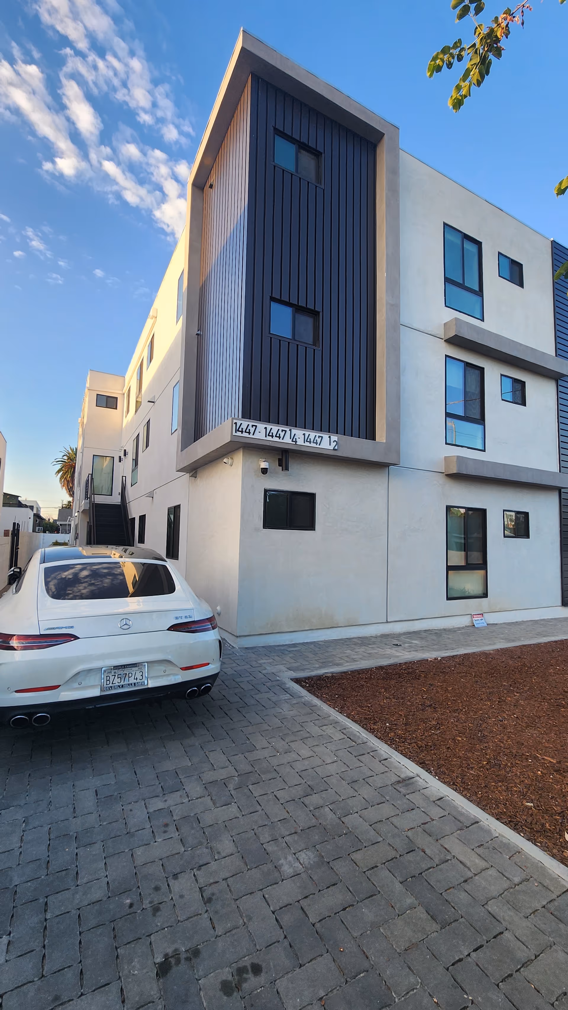 Modern multi-story senior living building with a parked white car in a paved driveway.