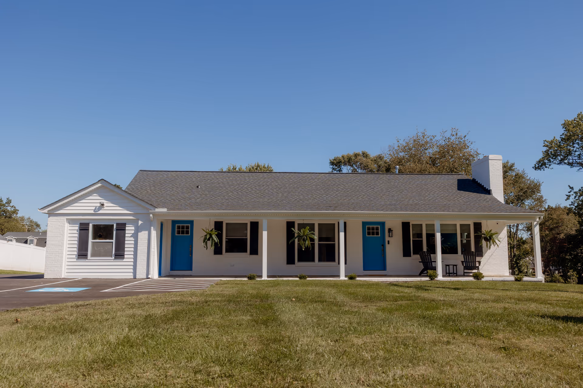 A single-story white building with blue doors and a covered front porch.