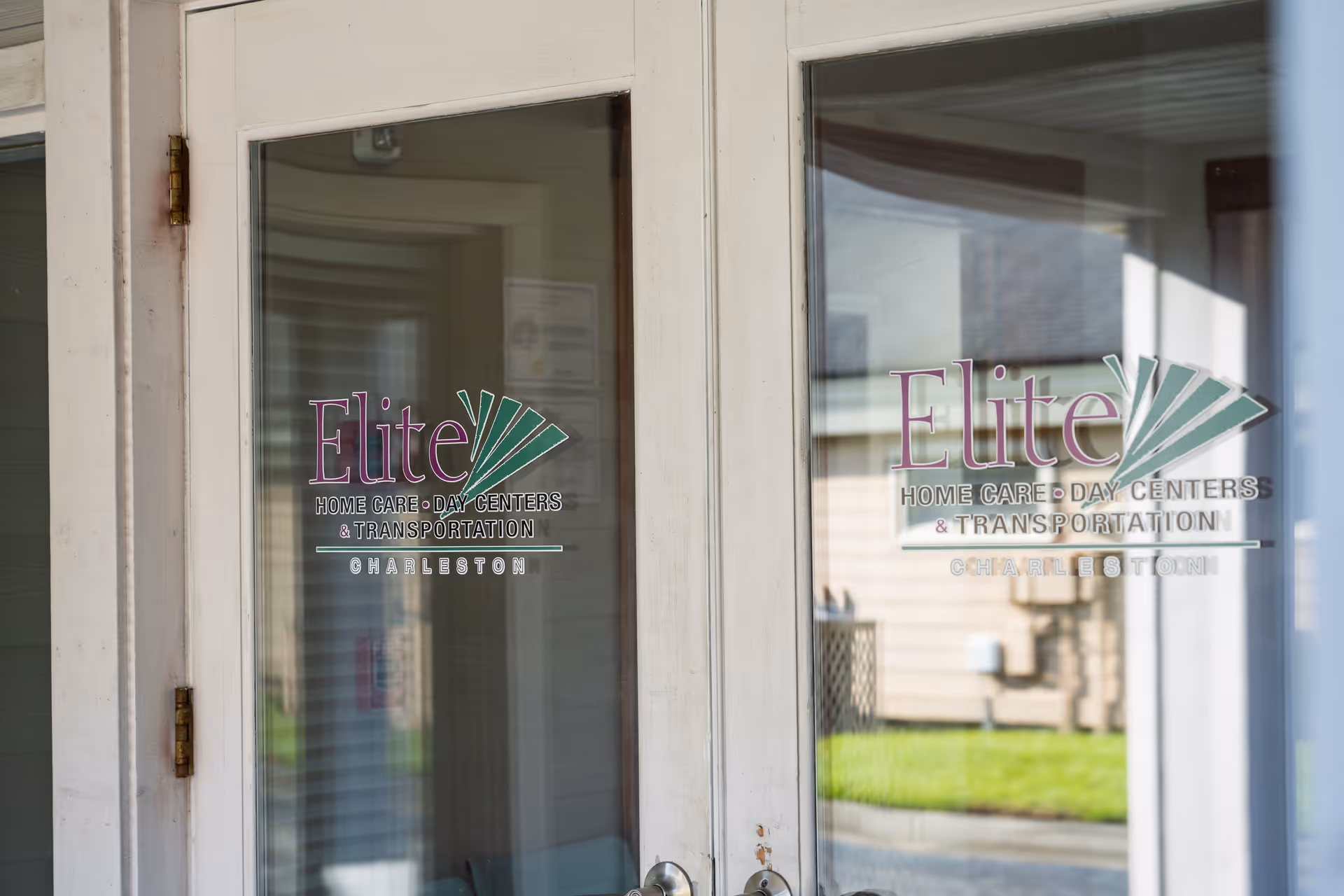 Glass doors bearing Elite Home Care Day Centers logo at facility entrance