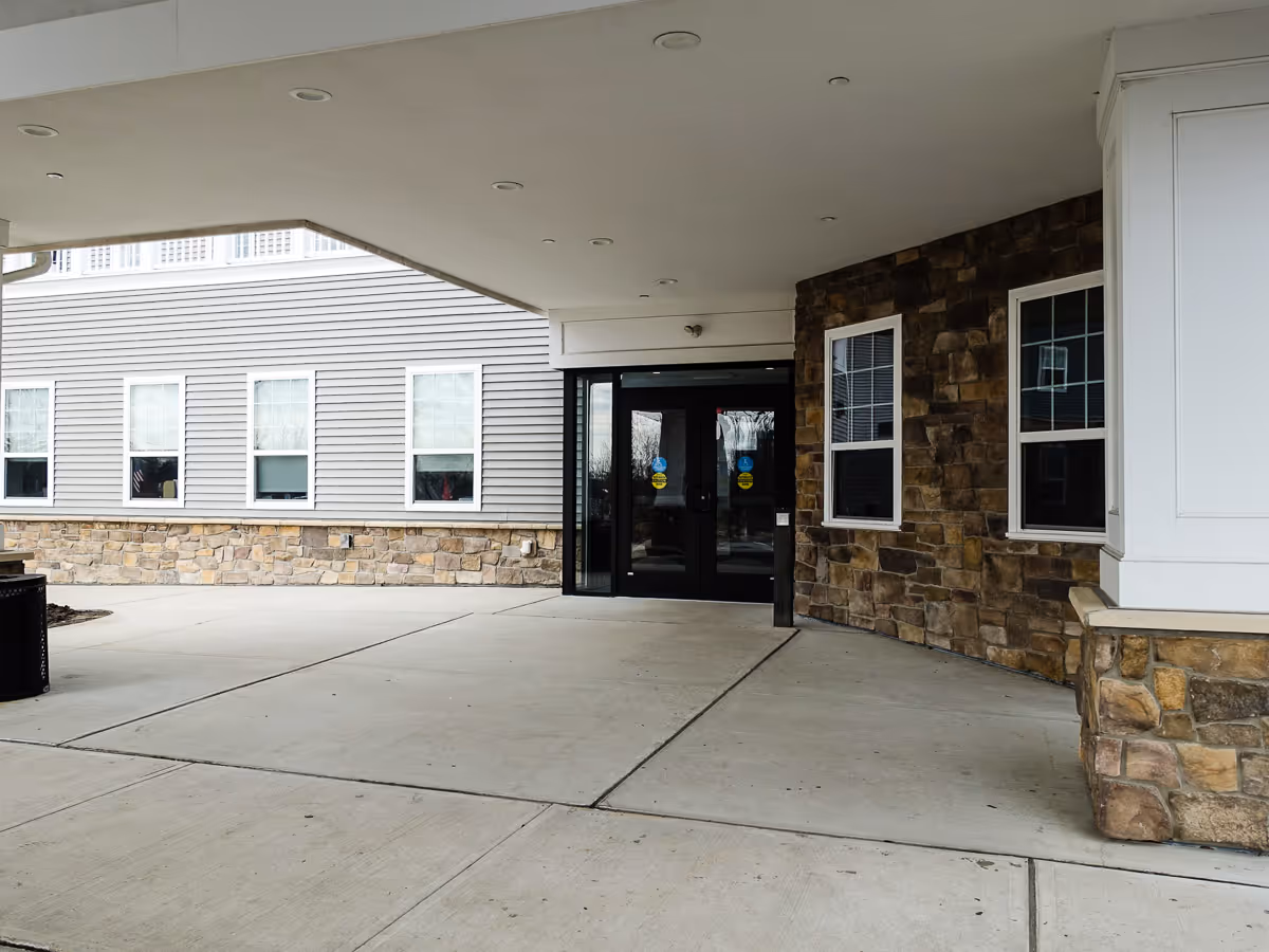 Covered entrance of the facility with glass doors and stone facade.