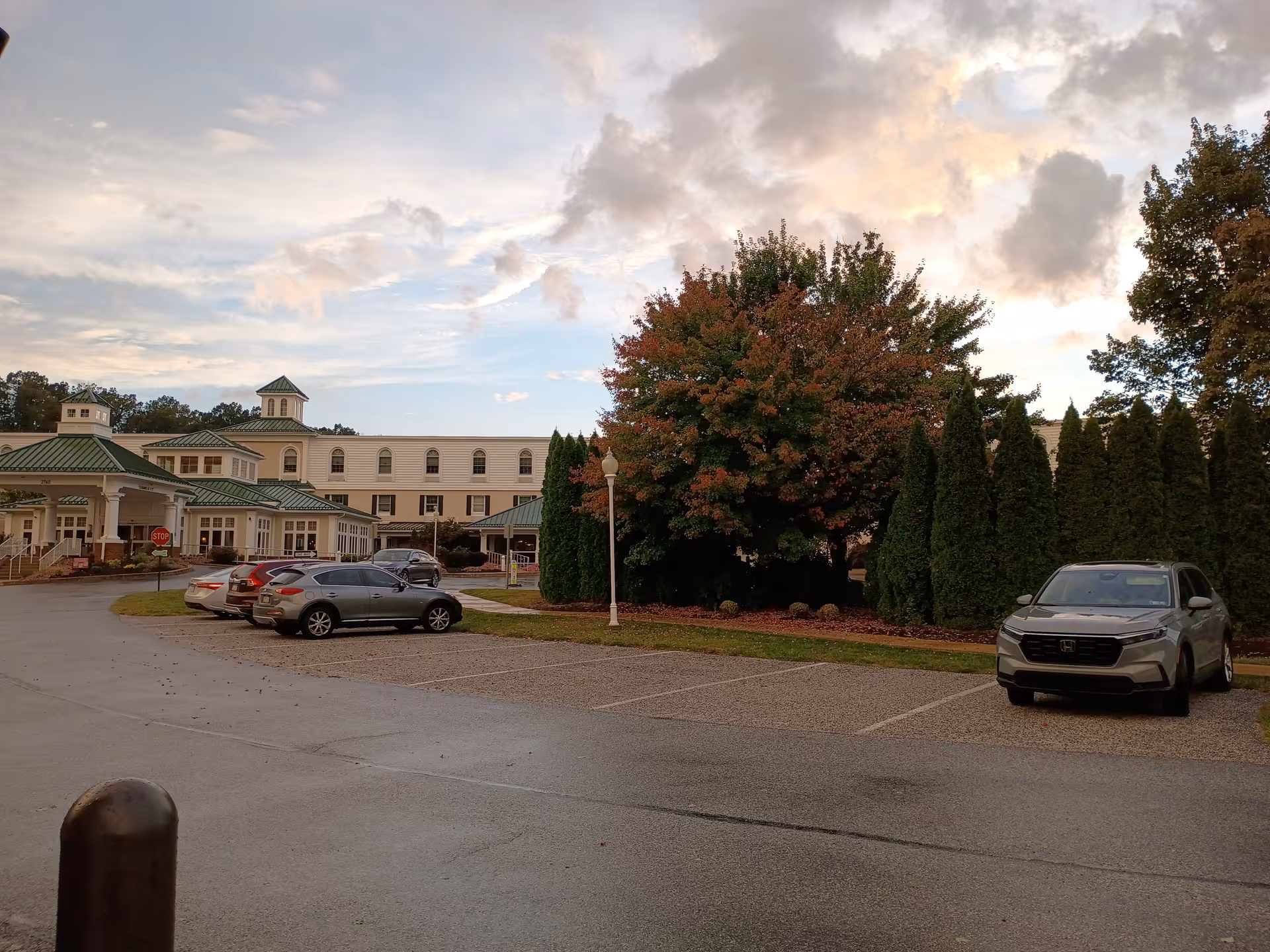 Exterior view of a Country Meadows retirement community with parked cars and surrounding trees.