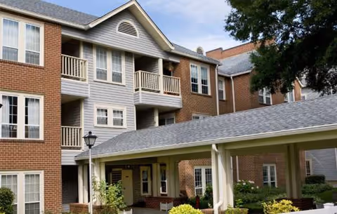 Brick senior living facility exterior with balconies and a covered entryway.