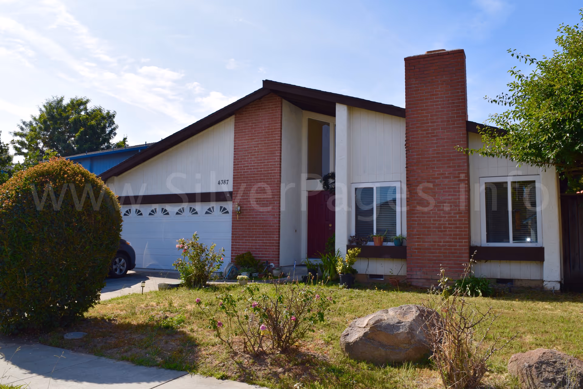Single-story suburban home with brick chimney and front yard landscaping.