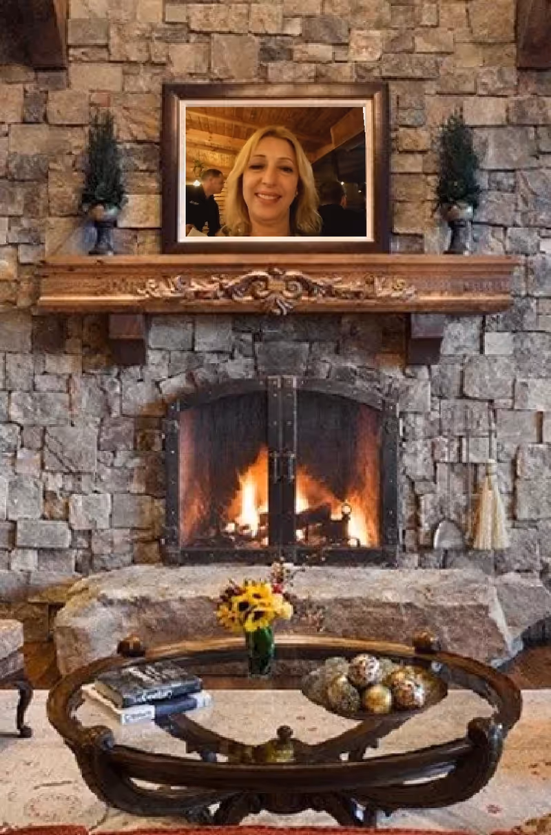 Framed picture above a carved mantel, with a lit stone fireplace and glass coffee table.