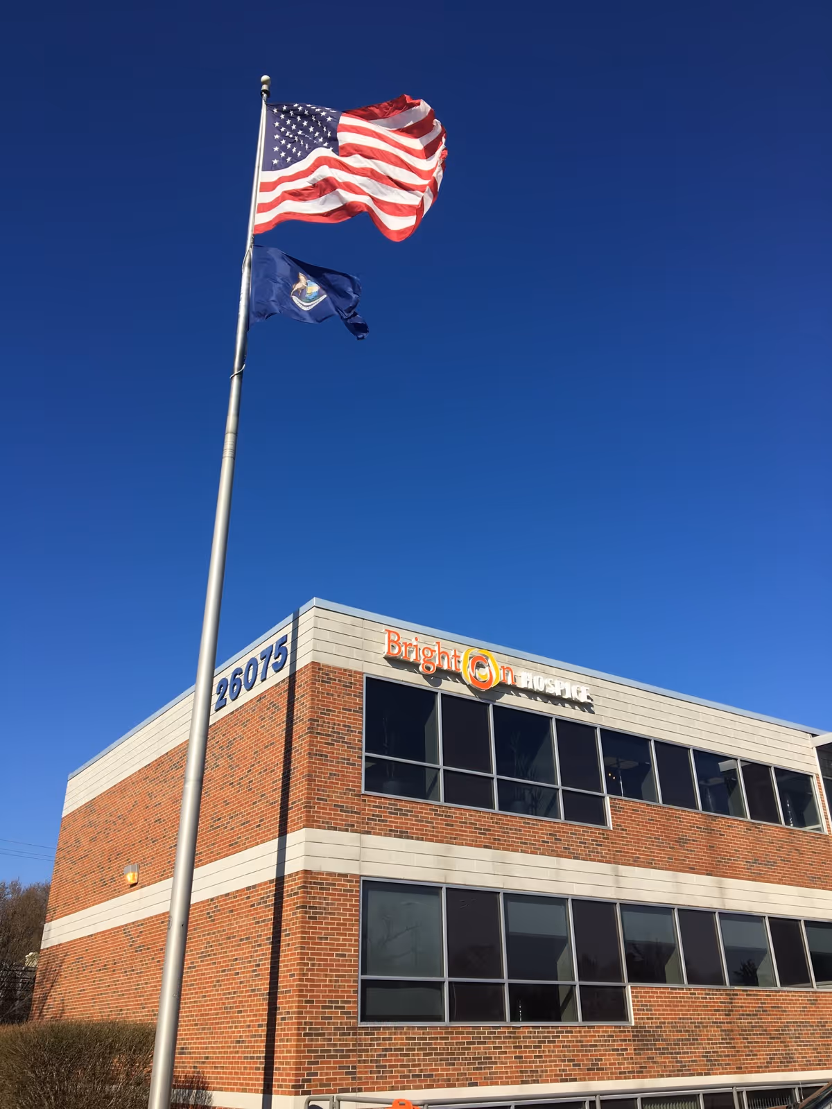 American flag on a flagpole beside Brighton Hospice building exterior.
