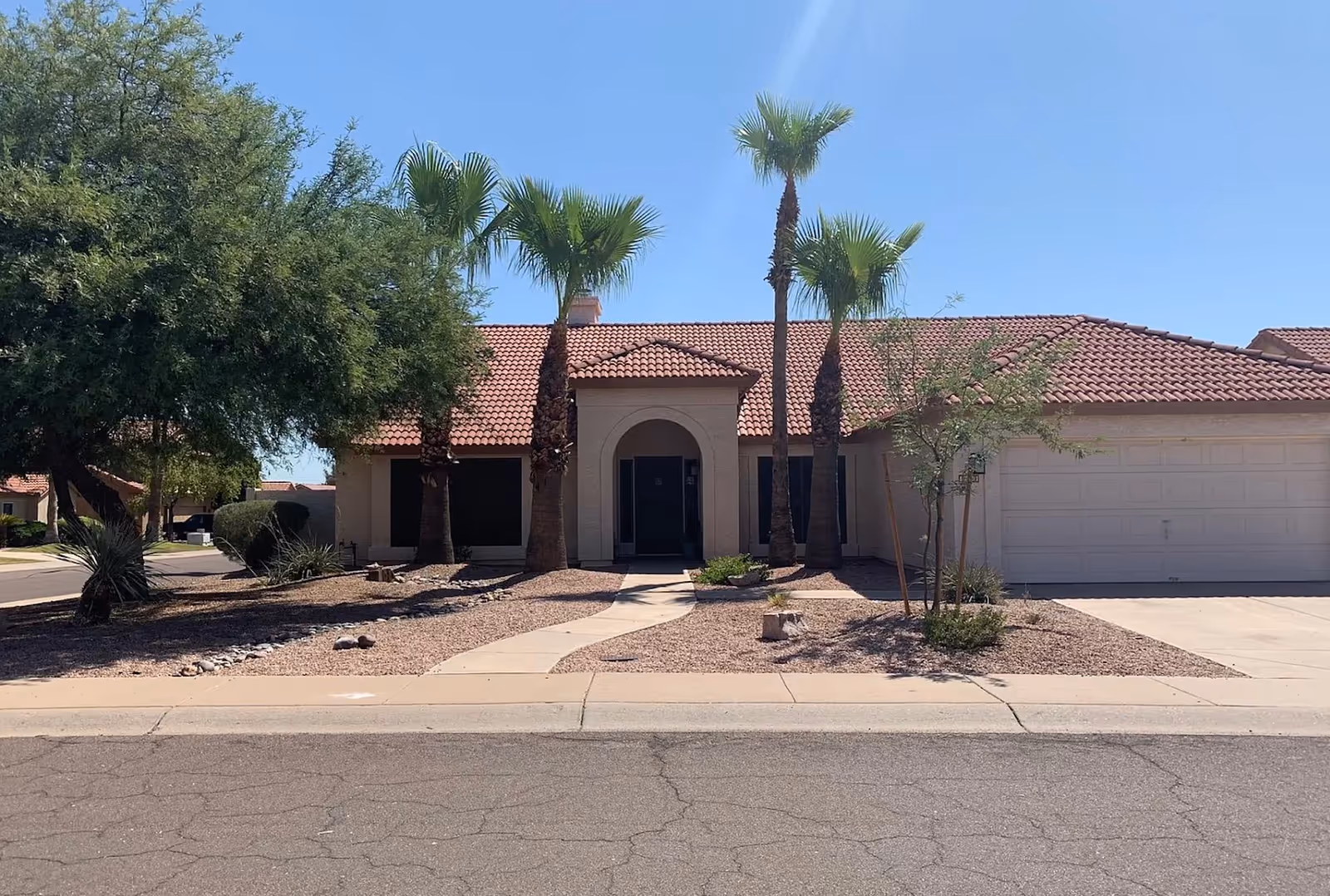 Front exterior of a single-story assisted living facility with palm trees and desert landscaping.