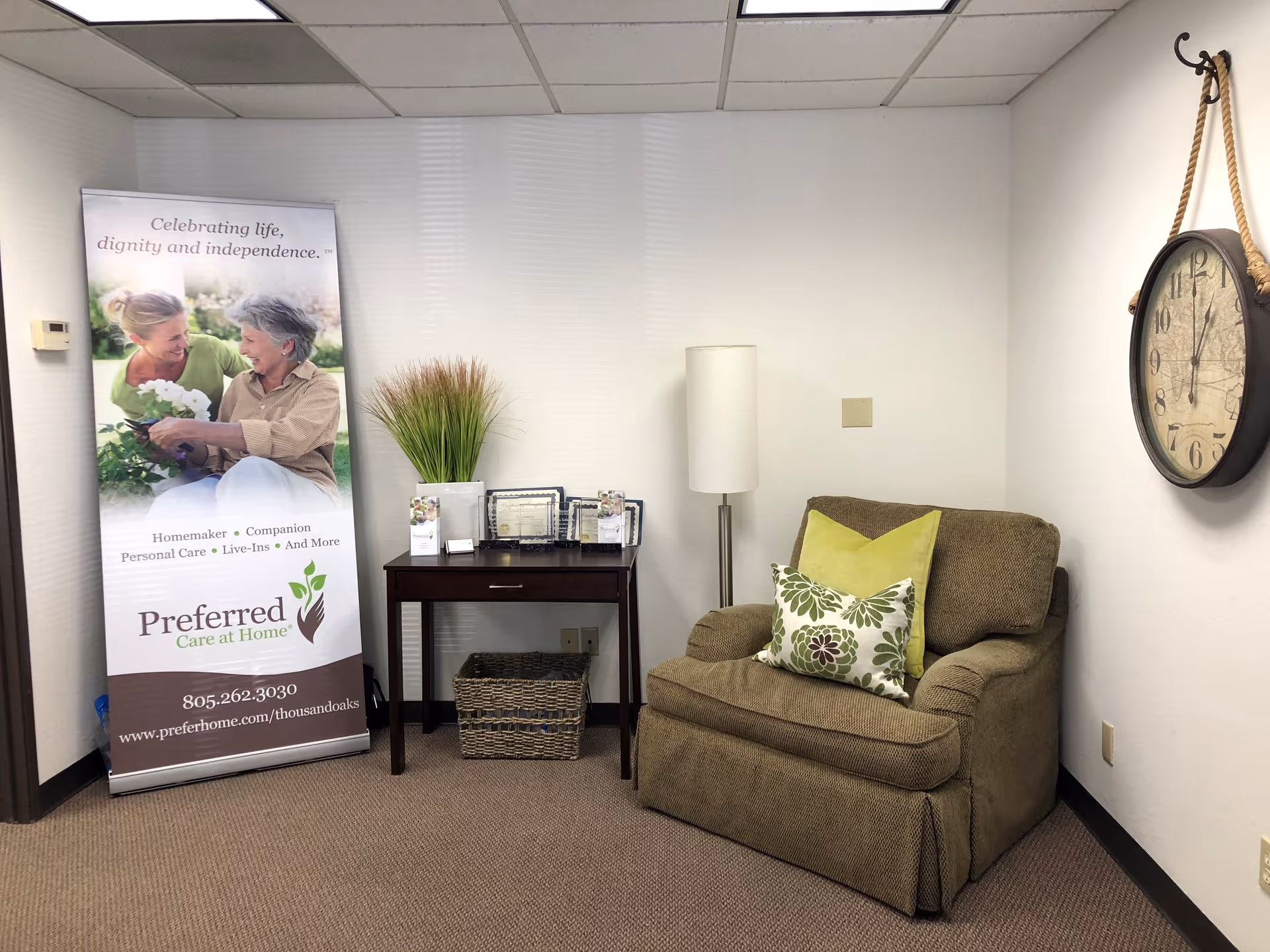 Cozy interior seating area with a banner, sofa, lamp, and wall clock.