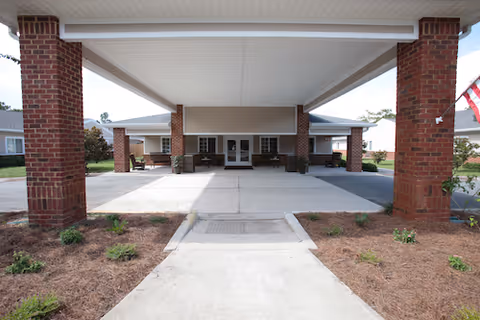 Covered entrance of St James Health and Rehabilitation Center with brick pillars and glass doors.