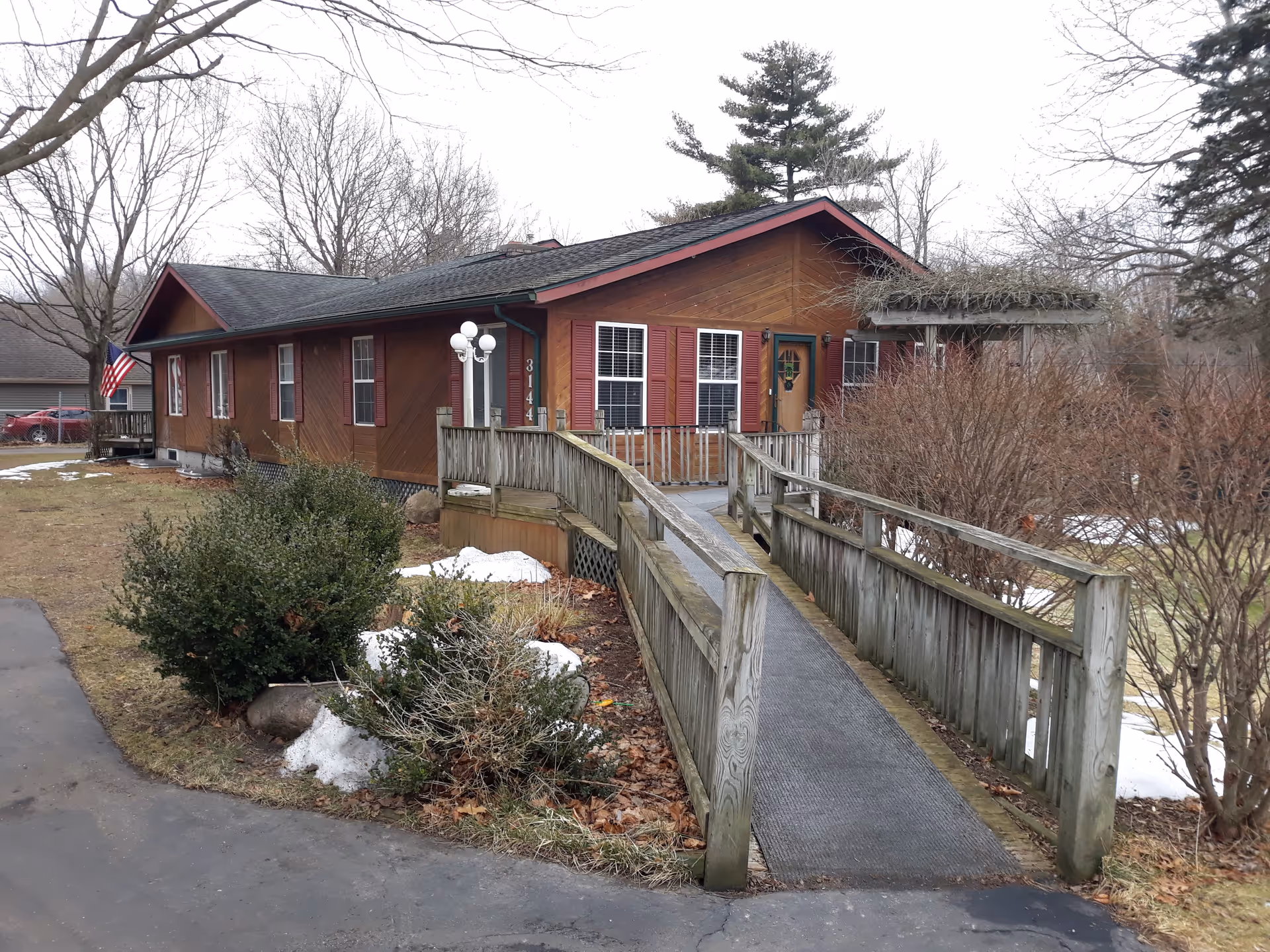 Brown single-story senior living facility with ramped entrance and leafless trees.