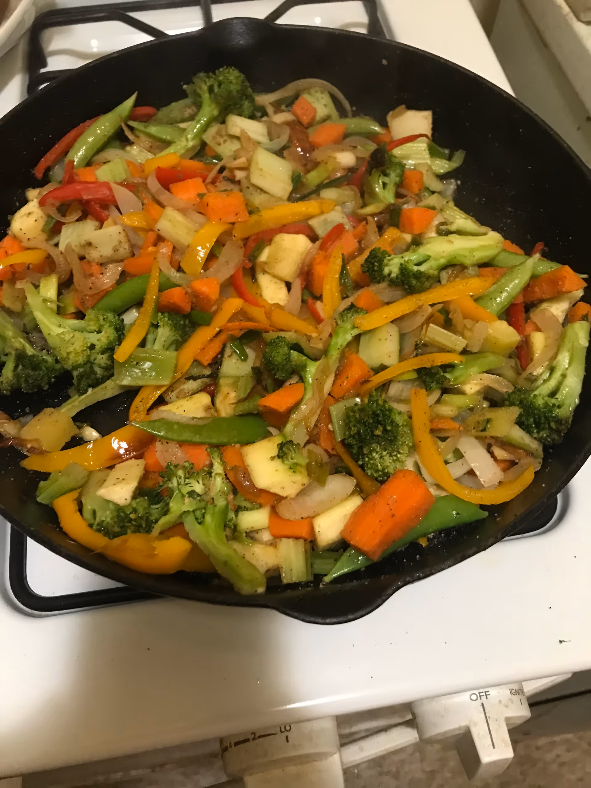 A colorful assortment of chopped vegetables sautéing in a skillet on a stove.