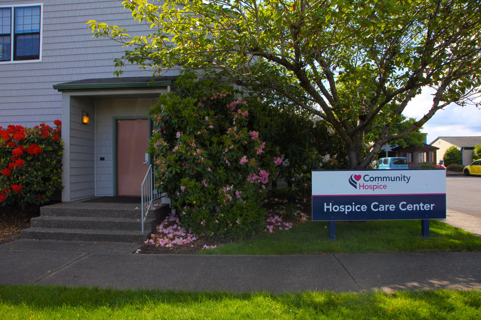 Exterior view of Community Hospice Care Center entrance with sign and greenery.